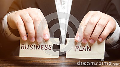 Businessman collects puzzles with the word Business Plan. Business operations program. Organization and management of processes Stock Photo