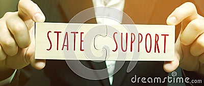 Businessman collects puzzles with the words State support. Tax relief. Protection of manufacturers in the domestic market and Stock Photo