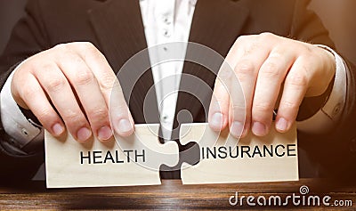 Businessman collects wooden blocks with the word Health insurance. Health care concept. Cash costs for medical care. Financial Stock Photo