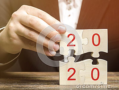 Businessman collects wooden puzzles with the inscription 2020. New Year concept. Plan, planning. Business goals and strategy for Stock Photo