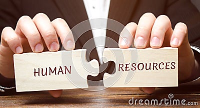 Businessman collects wooden puzzles with the word Human resources. Recruitment, HR, leadership and teambuilding. Business and Stock Photo