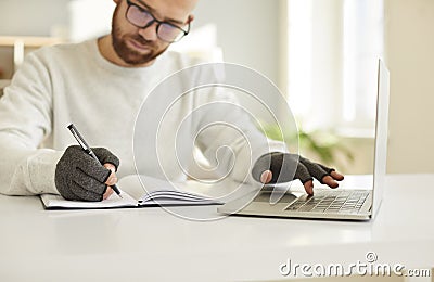 Businessman in compressive gloves work on computer write notes Stock Photo