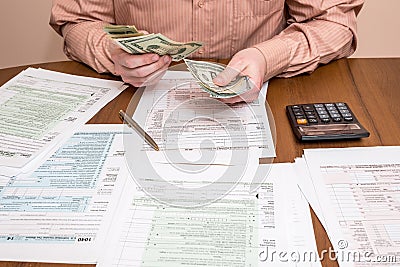 Businessman counting dollars with tax forms Editorial Stock Photo