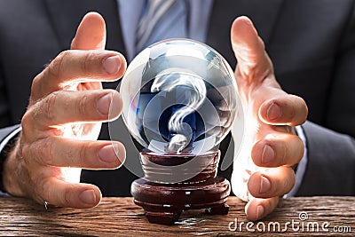 Businessman Covering Crystal Ball With Question Mark Stock Photo