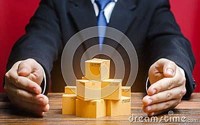 Businessman covers cardboard boxes with goods with his hands. Support for the manufacturer, attracting investment and promoting Stock Photo