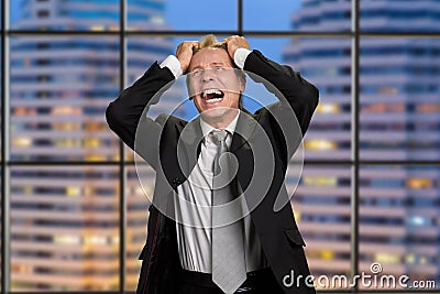 Businessman in despair on skyscraper background. Stock Photo