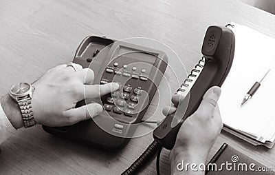 The businessman dials the number on the landline phone, holds the handset in his right hand Stock Photo