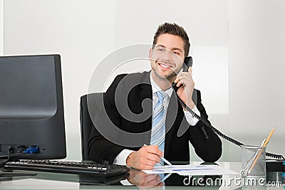 Businessman discussing over documents on telephone at desk Stock Photo