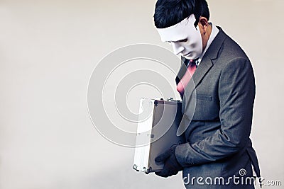 Businessman in disguise mask stealing a confidential suitcase - with copyspace Stock Photo