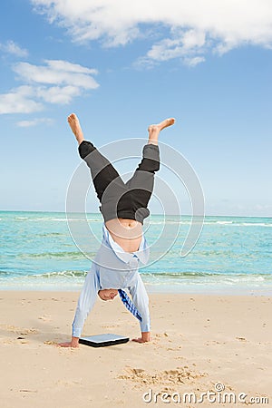 Businessman doing handstand on the beach Stock Photo