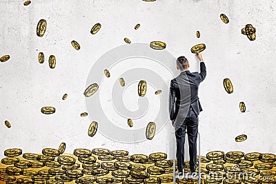 A businessman draws many golden dollar coins flying in a huge pile on a white wall. Stock Photo