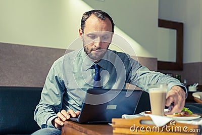 Businessman eating breakfast at home/hotel. Indoor photo. He is Stock Photo