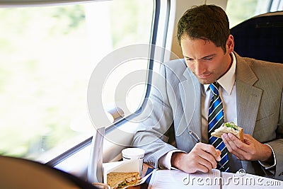 Businessman Eating Sandwich On Train Journey Stock Photo