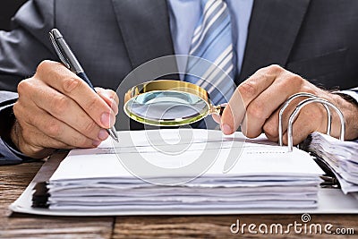 Businessman Examining Invoice With Magnifying Glass Stock Photo