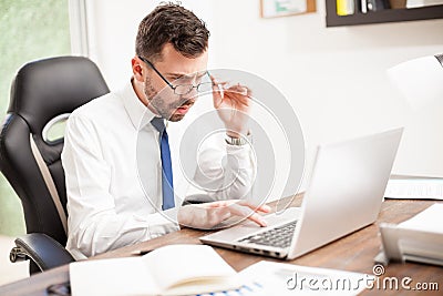 Businessman with eye fatigue working in an office Stock Photo