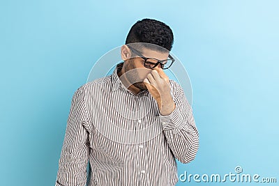 Businessman in eyeglasses rubbing his eyes, being tired of long hours working on laptop. Stock Photo