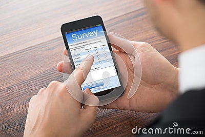 Businessman Filling Online Survey On Mobile Phone Stock Photo