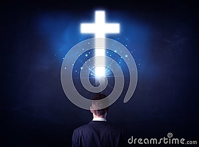 Businessman in front of a glowing cross Stock Photo