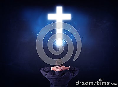 Businessman in front of a glowing cross Stock Photo