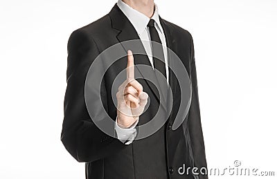 Businessman and gesture topic: a man in a black suit with a tie shows an index finger upward on white isolated background in Stock Photo