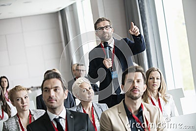 Businessman gesturing while asking question during seminar in convention center Stock Photo