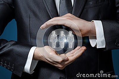 Businessman gesturing hands protects holograms of workers Stock Photo