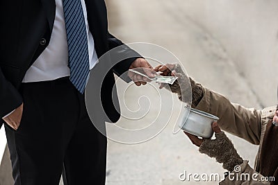 Businessman give money to homeless man in city Stock Photo