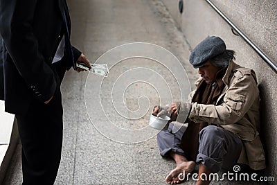 Businessman give money to pity homeless Stock Photo