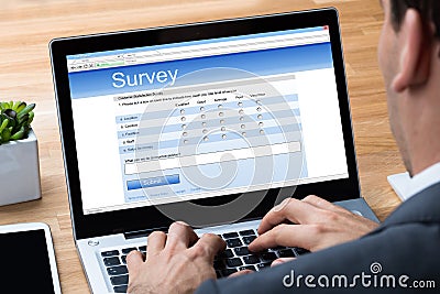 Businessman Giving Online Survey On Laptop Stock Photo