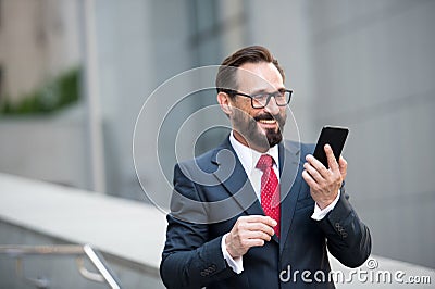 Businessman in glasses using smart phone on office walkway with city building background. Concept of business people Stock Photo