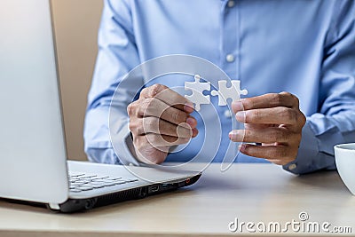 Businessman Hand connecting couple puzzle piece in office. Business solutions, mission, successful, goals and strategy concepts Stock Photo