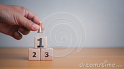 Businessman hand holding a king placed on the topmost layer of wood. It represents the concept of competition and strategic Stock Photo