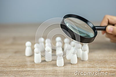 Businessman hand holding magnifying glass for recruiting leader man wooden from crowd of employees. People, Business, Human Stock Photo