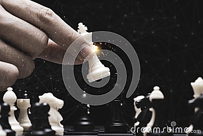 Businessman hand holding and moving white king chess figure with competitor to success play. Business management competition and Stock Photo