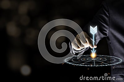 Businessman hand holding and throwing virtual dart to target board on black background.Business and investment target concept Stock Photo