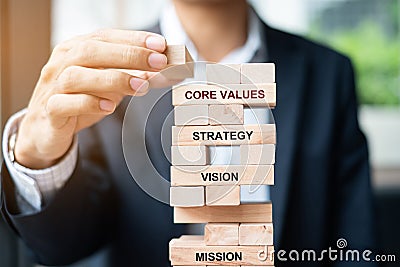 Businessman hand placing or pulling wooden block on the tower. Business planning, Risk Management, Solution, Mission, Vision, Core Stock Photo