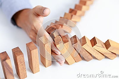 Businessman hand protect wooden toy block from danger and fall Stock Photo