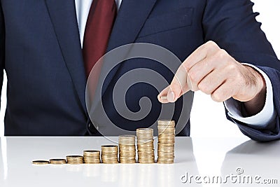 Businessman hand stacking one euro coins into increasing columns Stock Photo