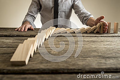 Businessman hand stopping domino effect Stock Photo