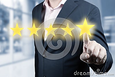 Businessman hand touching five star symbol. Man Is Pointing Five Stars - Review And Rating Concept. blurred office background Stock Photo