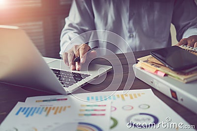Businessman hand working laptop on wooden desk in office in morning light. The concept of modern work with advanced technology. Stock Photo