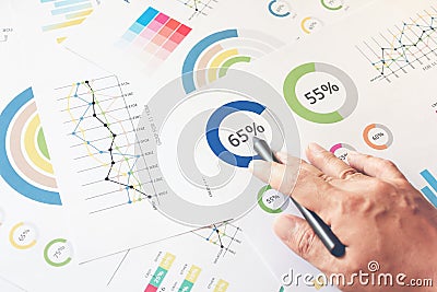 Businessman hand working on wooden desk in office and there are many documents, graphs. Can be attributed to financial articles Stock Photo