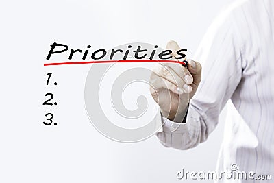 Businessman hand writing Priorities with red marker on transparent wipe board, business concept Stock Photo