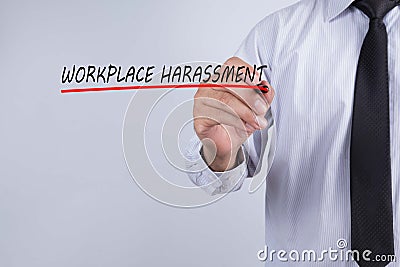 Businessman hand writing workplace harassment word with red marker on transparent wipe board, business concept Stock Photo