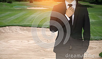 Businessman handles necktie showing confidence in golf course. Stock Photo