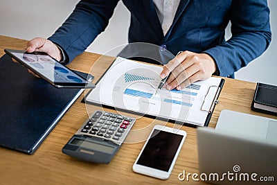 Businessman hands using text information on digital tablet to analyze financial statistical chart data and calculate cost of Stock Photo