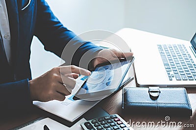 Businessman hands using text information on digital tablet to analyze financial statistical chart data and calculate cost of Stock Photo