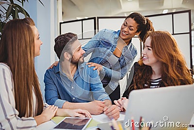 Businessman with happy female coworkers at desk Stock Photo