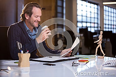 Businessman having coffee while reading document Stock Photo