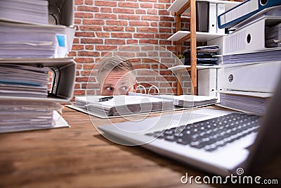 Businessman Hiding Behind The Desk Stock Photo